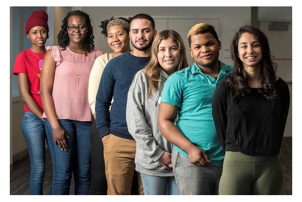Racially diverse students of varying genders standing in a row, smiling.