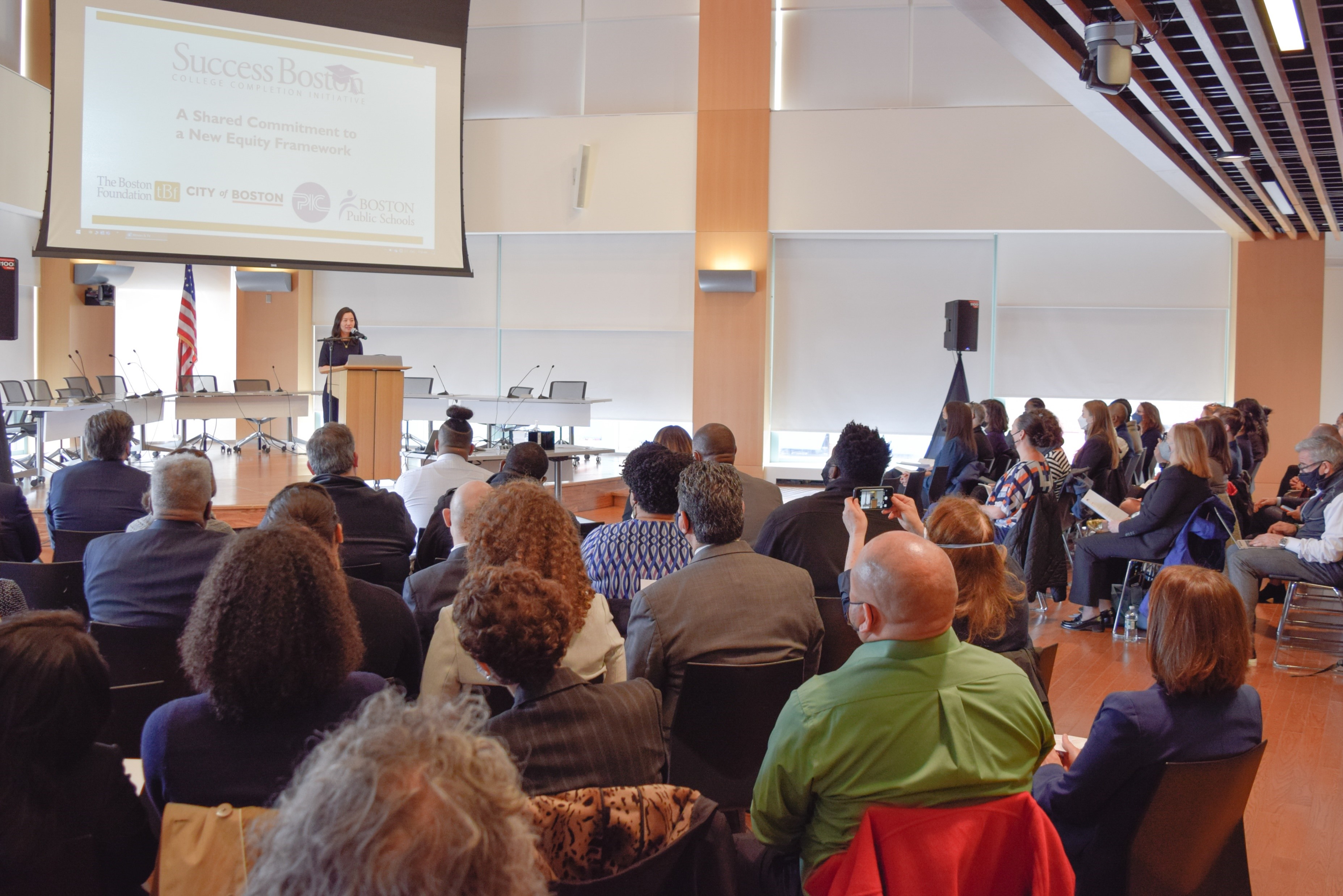 At a Success Boston event, Mayor Michelle Wu presents onstage in an auditorium surrounded by seated guests.